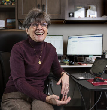 Montana’s Health Policy MVP Takes Her Playbook on the Road Photo of Marilyn Bartlett sitting at her desk smiling